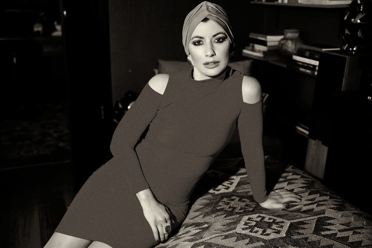 services-04 Black and white portrait of a stylish woman in a dress, wearing a turban, elegantly posing indoors.